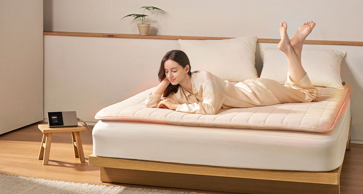 침대 위 셀트론 순환 매트 전체가 따뜻하게 데워진 가운데 엎드려 휴식하는 여성
